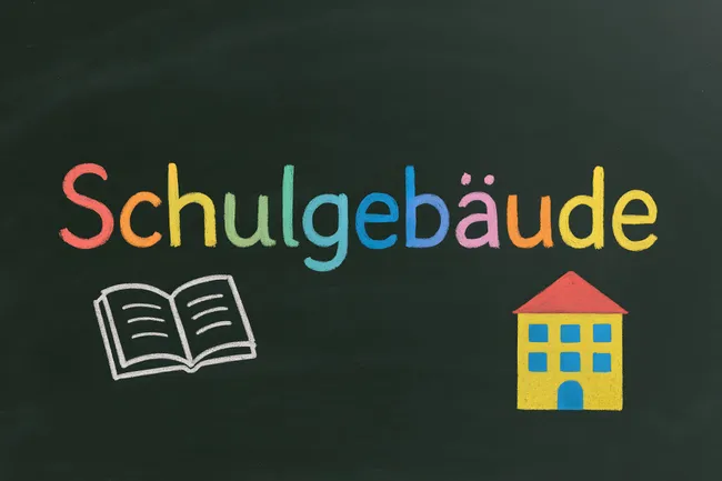 Kreidezeichnung eines Schulgebäudes und Wort 'Schulgebaude'