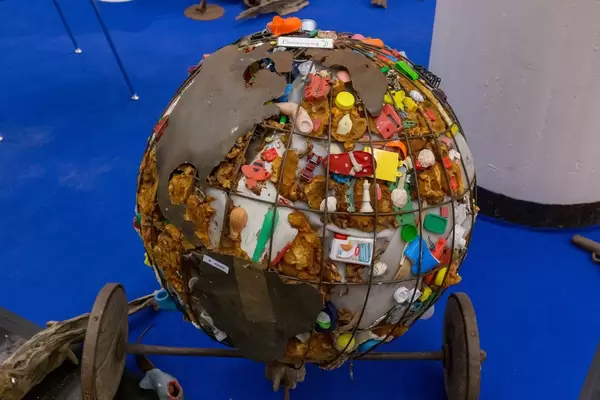 Kritisches Kunstobjekt Weltkugel aus Metall mit Kontinenten und Müll in den Ozeanen