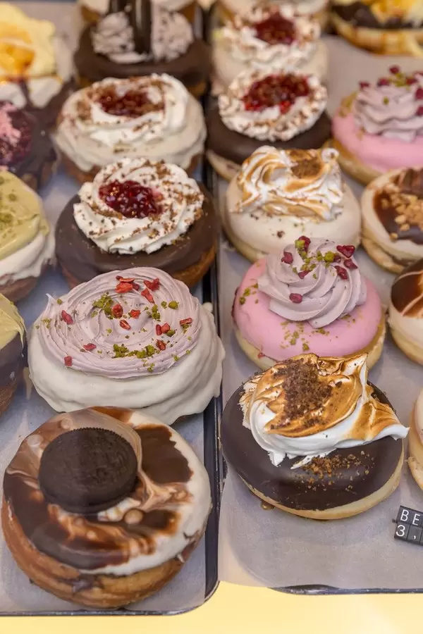 Kronut and Berlina Pastries with creme topping, Oreos, grated pistachios and dried petals by vegan shop "chök" in Barcelona, Spain