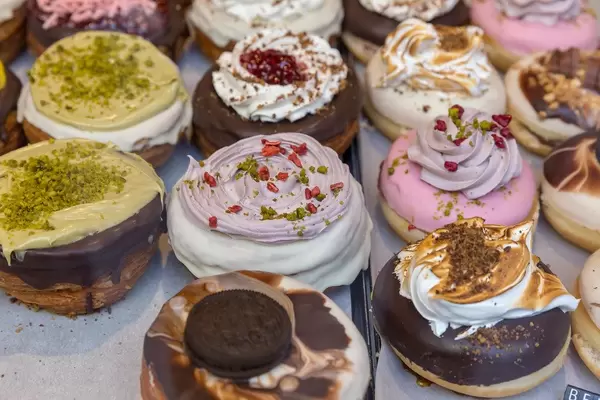 Kronuts: Veganes Blätterteigebäck von chök, mit Schokoladenglasur, geraspelten Pistazien, Blumenblättern und Oreos, in Barcelona, Spanien