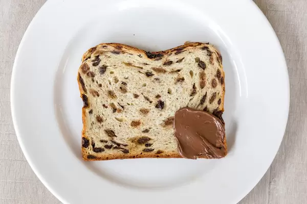 Kuchen mit gedörrten Früchten und Rosinen, an einer Ecke mit Schokolade-Nuss-Aufstrich