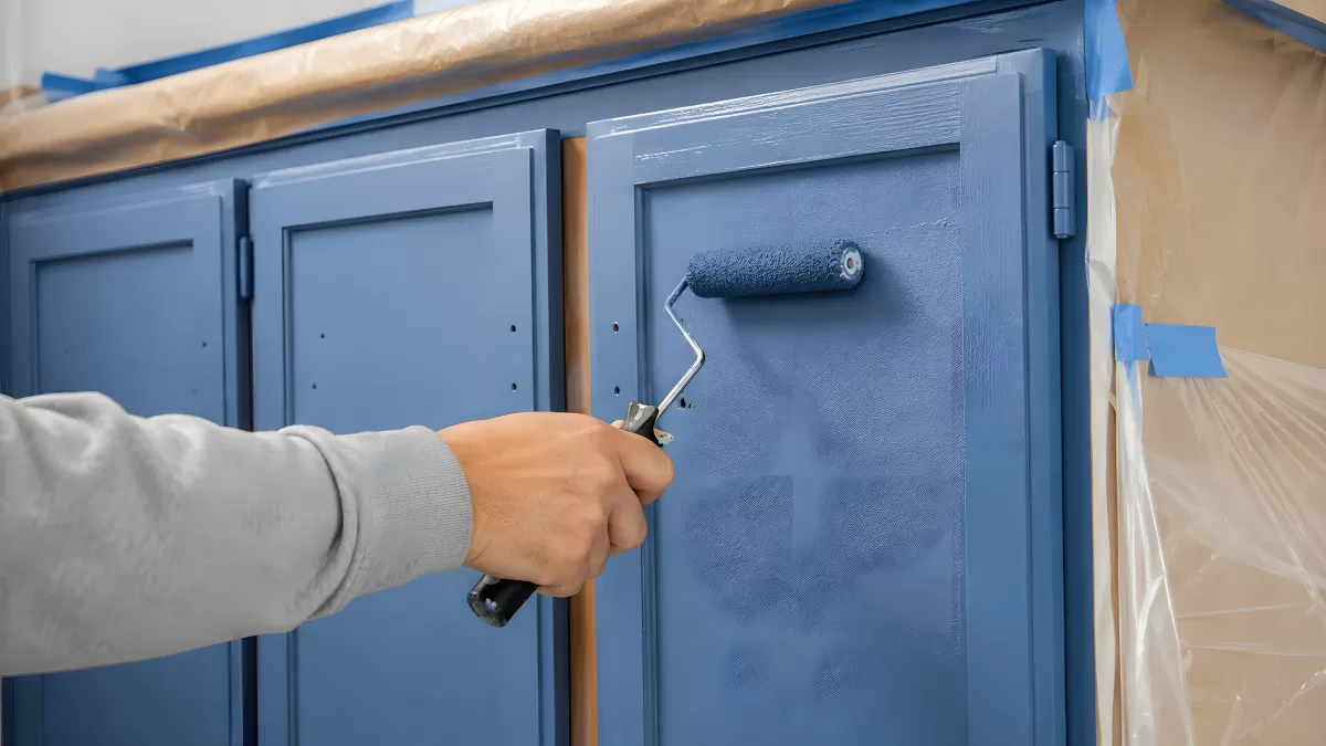 Küchenschränke mit blauer Farbe und Lackierrolle streichen