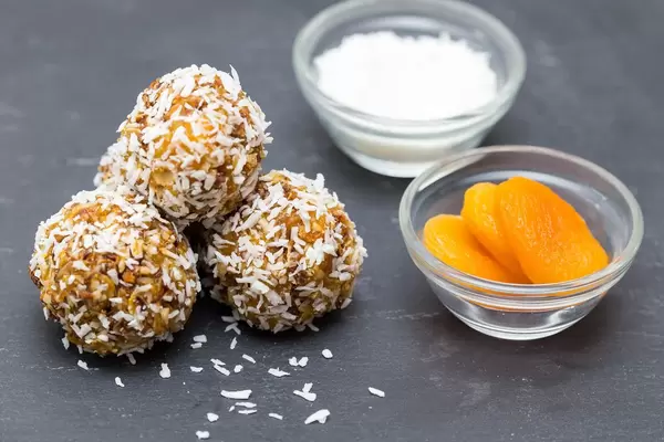 Kügelchen aus karamelisierten Haferflocken mit Kokos und getrockneten Aprikosen