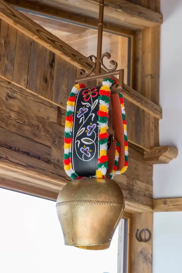 Kuhglocke mit buntem Band hängt in einem Gebäude aus Holz in den Alpen in Tirol