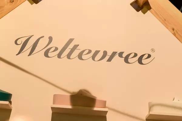 Kultige Holzschuhe in unterschiedlichen Farben vor Schild der Marke Weltevree