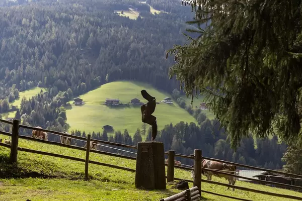 Kunst und Landschaft in den Alpen: eine Skulptur und Kühen auf der Weide im Hintergrund in Alpbach