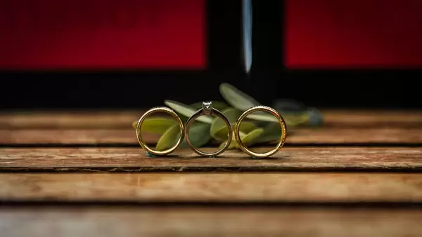 Künstlerisches Foto von Eheringen auf Holzlatten vor Blättern mit Bokeh-Effekt im Hintergrund