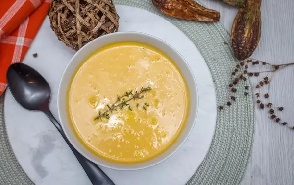 Kürbiscremesuppe mit einem Zweig Thymian in einer Schüssel mit Dekorationen in der Aufsicht