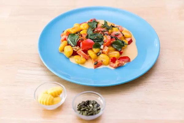 Kürbisgnocchi in Paprikasoße mit Zutaten in kleinen Schalen