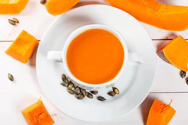 Kürbissuppe in einer Terrine auf einer Draufsicht des weißen Holztischs