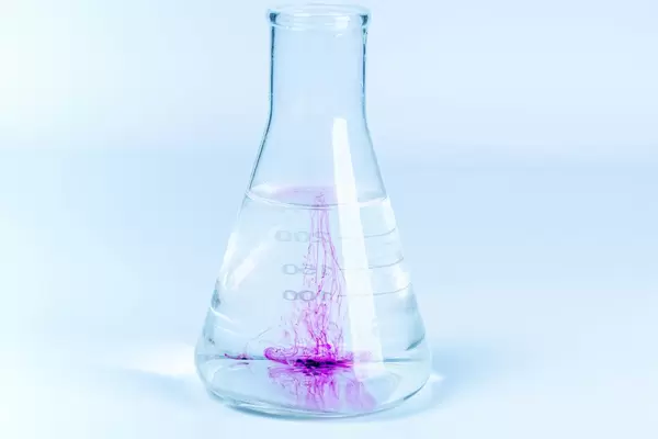 Laboratory flask with liquid and dissolving cristamimium potassium permanganate