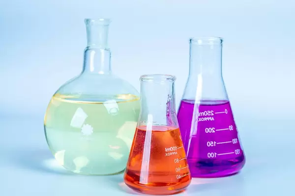 Laboratory glassware with colored liquids on light background (Flip 2020)
