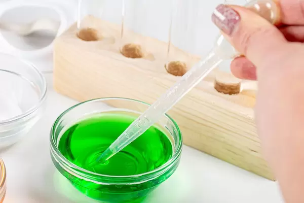 Laboratory tests background. Green solution and a female hand with a pipette (Flip 2020)