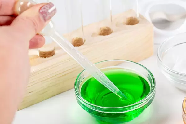 Laboratory tests background. Green solution and a female hand with a pipette