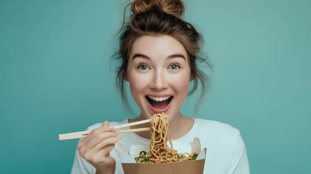 Lachende Frau genießt asiatische Nudelgerichte