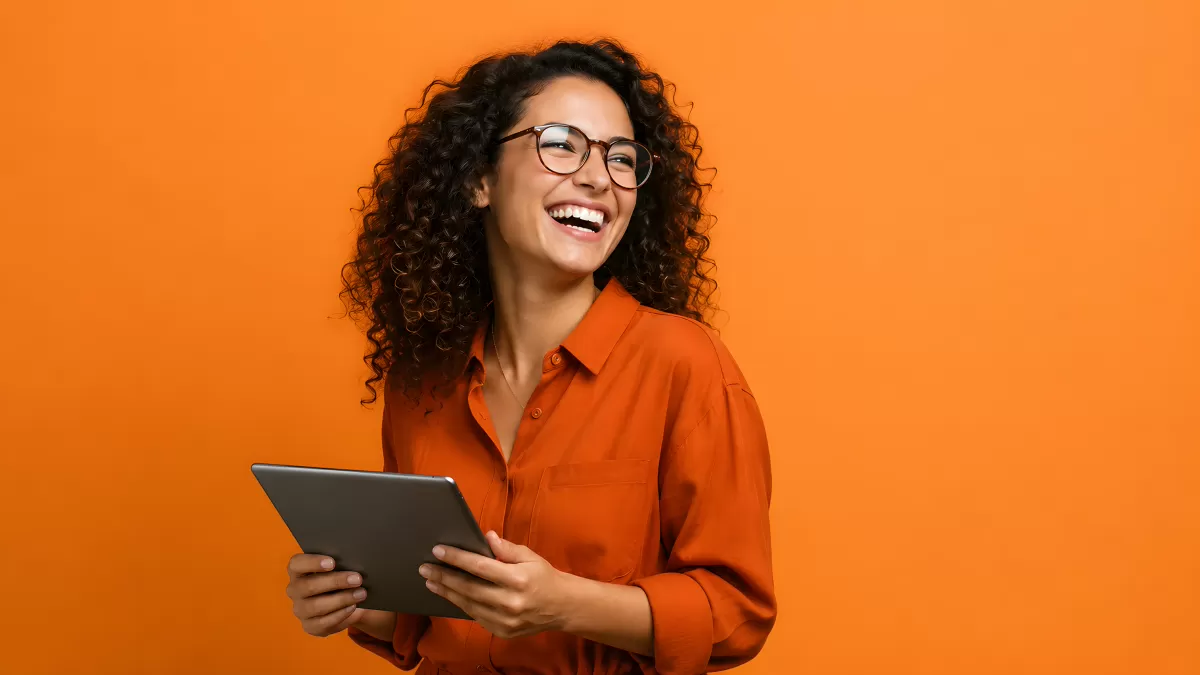 Lachende Frau mit Tablet vor orangem Hintergrund