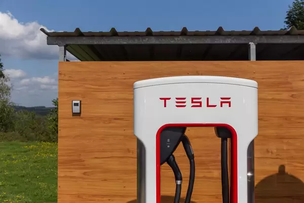 Ladesäule "Supercharger" von Tesla, zum Schnellladen von Elektrofahrzeugen, vor einer Holzwand