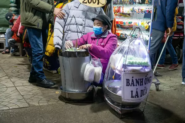 Lady selling Vietnamese Pineapple Leaf Tube Cake Banh Ong La Dua at the famous Night Market in Da Lat, Vietnam