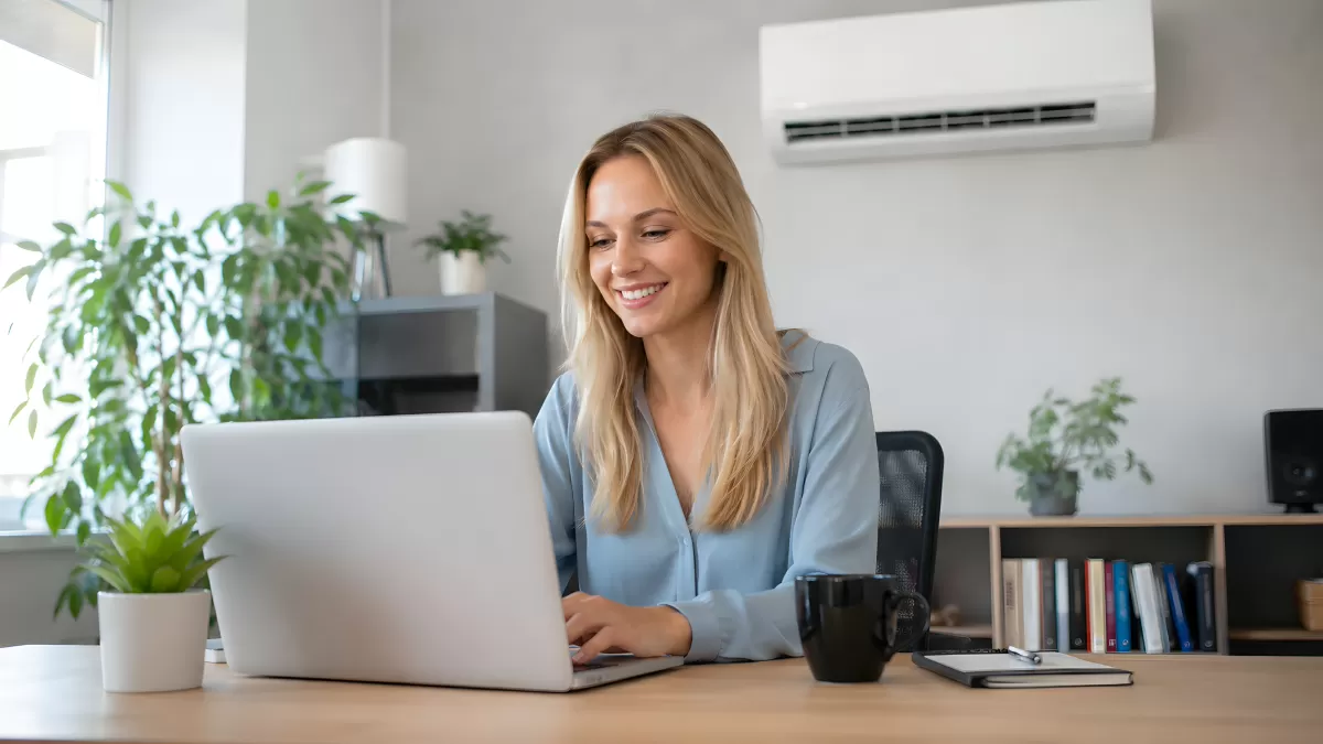 Lächelnde Frau arbeitet im Homeoffice am Laptop
