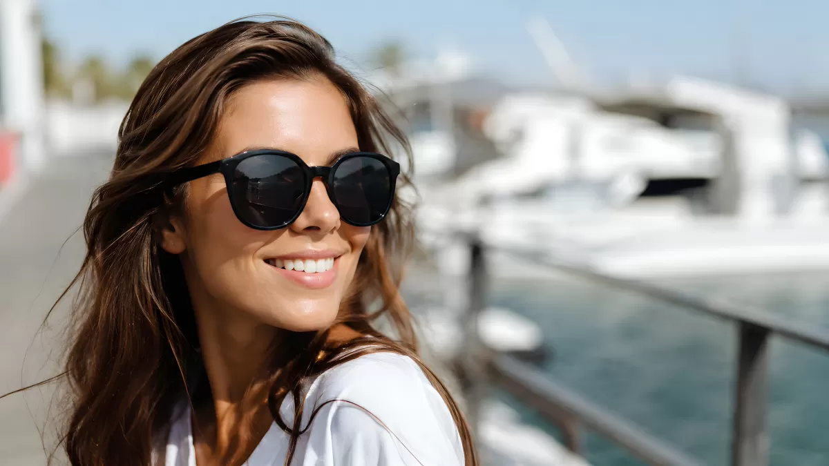 Lächelnde Frau mit Sonnenbrille am Yachthafen
