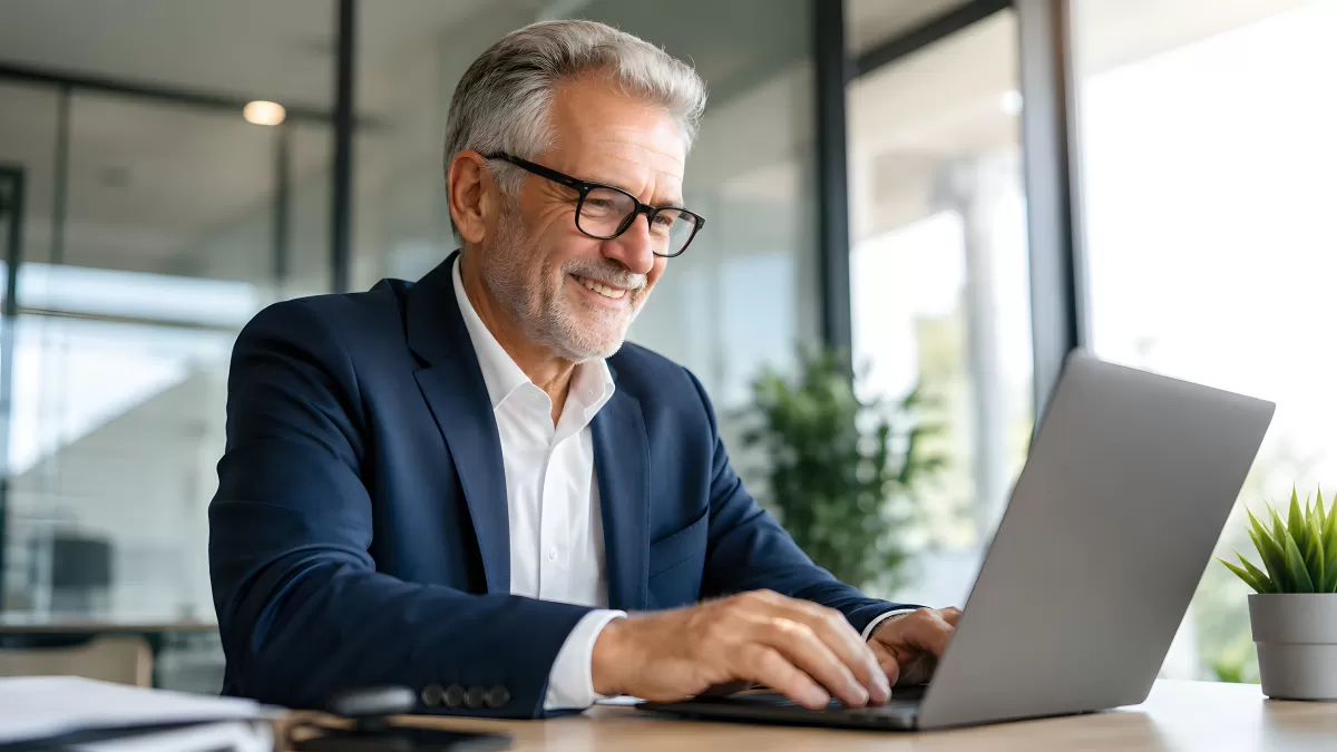 Lächelnder Geschäftsmann arbeitet am Laptop im Büro