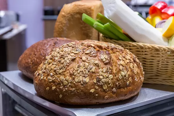 Laib Körnerbrot neben anderen Backwaren auf einem Tablett