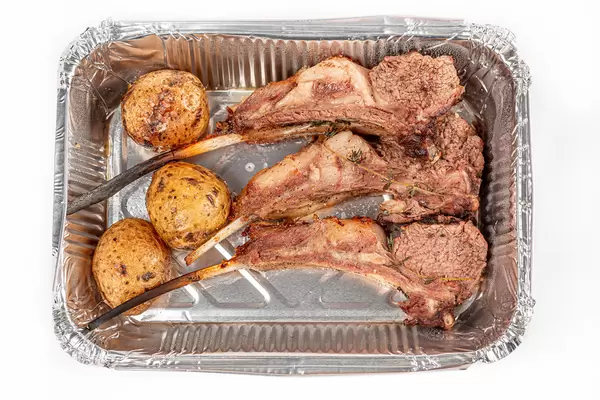 Lamb ribs with potatoes in a container, top view