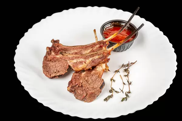 Lamb ribs with thyme and adjika on a white plate