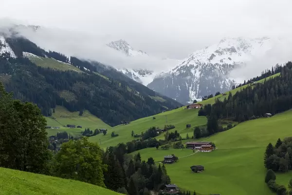 Landscape of the Alpbach valley with typical Tyrolean wooden houses and snowy mountains in the background