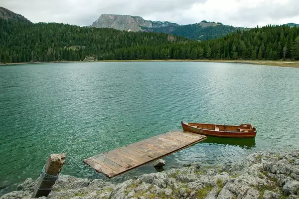 Landscape Photo of Wooden Rowing Boat in a Lake with Forest and Mountains in the Background at Durmitor National Park in Montenegro