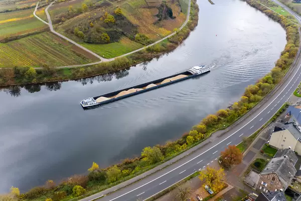 Langes Frachtschiff beladen mit Sand auf dem Fluss Mosel entlang der Bundesstraße B49 an der Ortsgemeinde Bremm in Deutschland