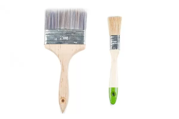 Large and small wooden paint brushes on a white background