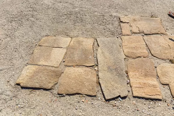 Large flat stones of gneiss: the paved ground of the Agora of the Competaliasts, ancient market on Delos