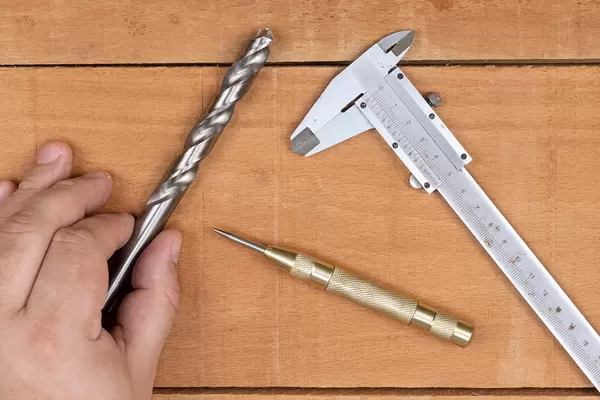 Large Metal Drill in the hand Nonius and Hole marker on the table