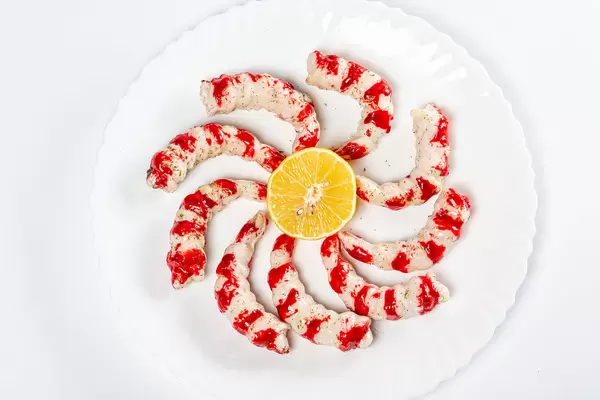 Large shrimp with lemon on a white plate, top view