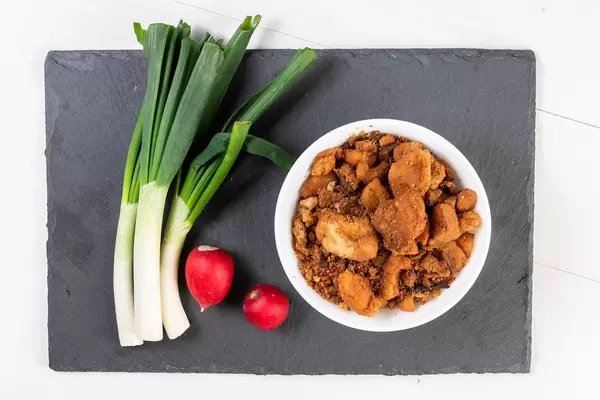 Lauch, rote Radieschen und Schweinefleisch auf schwarzem Schieferteller