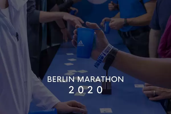Läufer am Adidas-Stand mit Getränkebechern und dem Bildtitel "Berlin Marathon 2020"