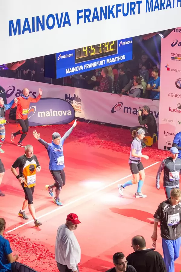 Läufer wirft seine Hände hoch beim überqueren der Ziellinie - Frankfurt Marathon 2017