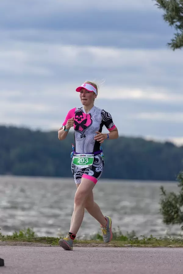 Läuferin rennt die 21,097 km Marathonstrecke am Seeufer in Lahti, Finnland, um den Ironman 70.3 erfolgreich zu beenden