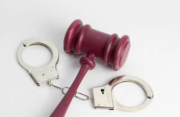 Law Gavel laying on Handcuffs on white Background