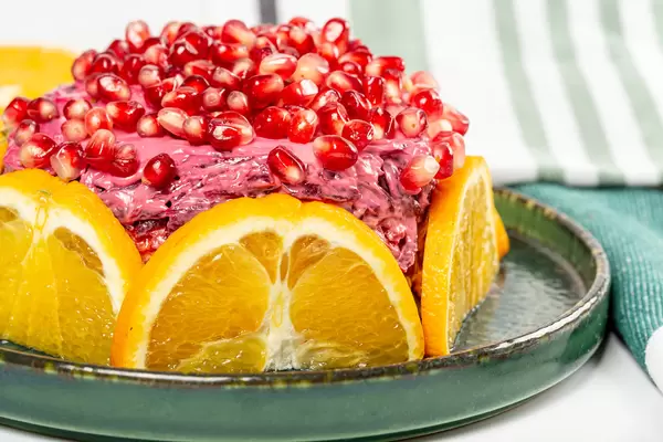 Layered salad composed of pickled herring covered with layers of boiled grated vegetables, orange and pomegranate