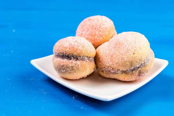 Leckeres Zuckergebäck auf weißem Teller auf blauem Holztisch
