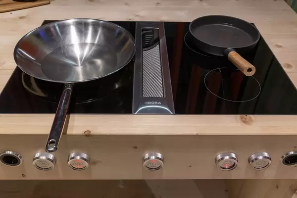 Leere Bratpfannen auf Kochfeld mit digitalen Reglern und integriertem Dunstabzug von Bora