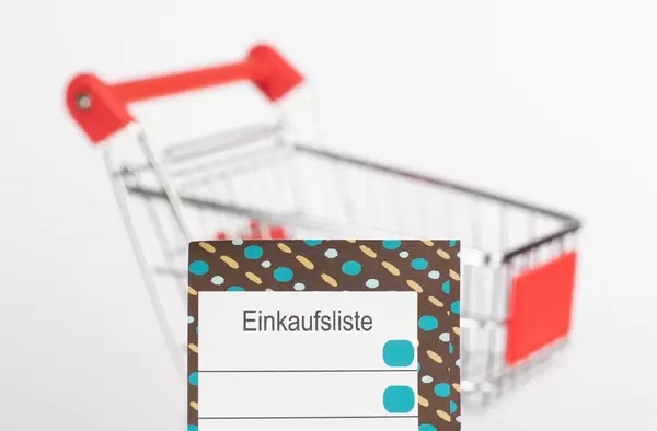 Leere Einkaufsliste mit Einkaufswagen im Hintergrund mit Schärfentiefe fotografiert