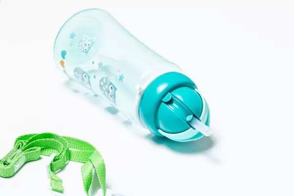 Leere Kinderflasche mit Tragegurt vor weißem Hintergrund