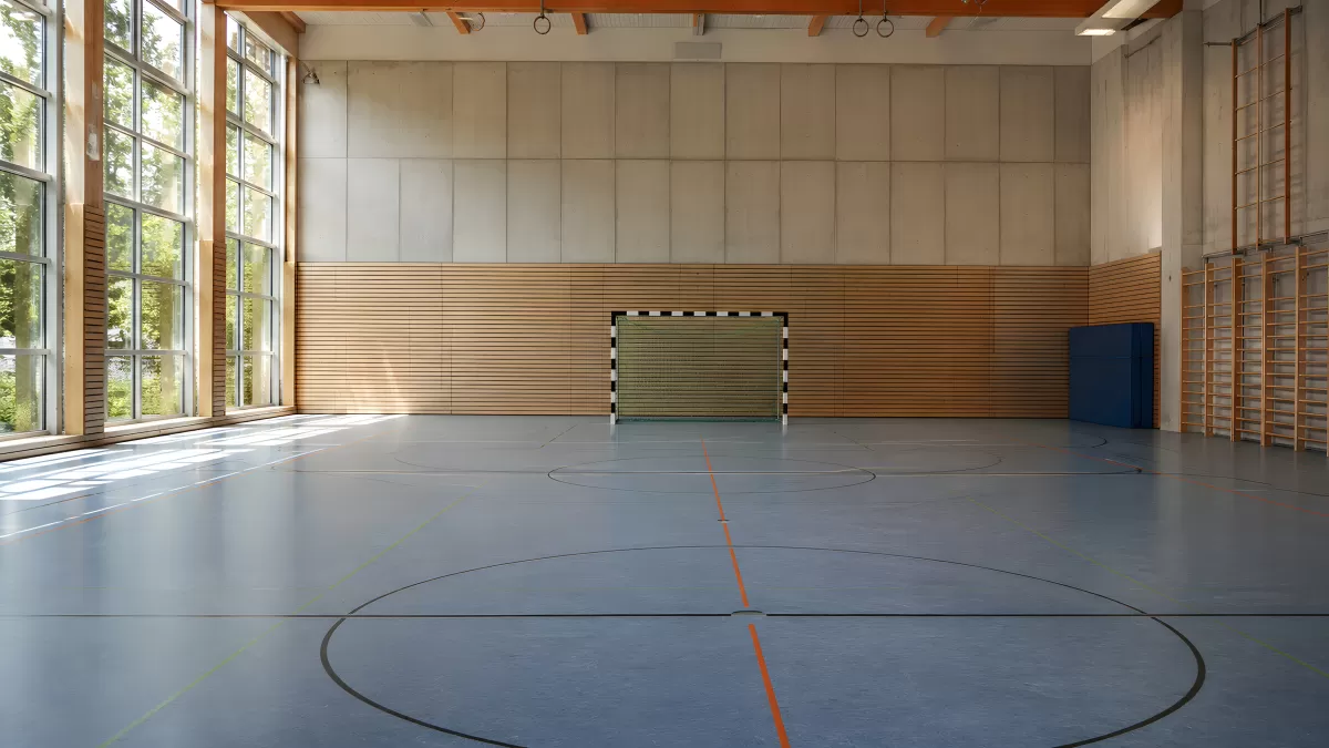 Leere Sporthalle mit Handballtor und Holzwand