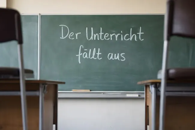 Leerer Klassenraum mit Tafel zur Mitteilung 'Unterricht fällt aus'
