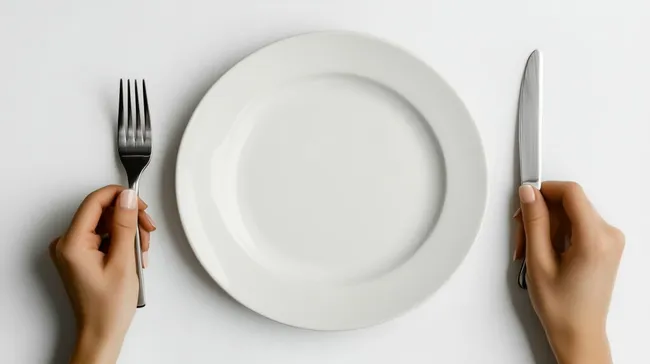 Leerer Teller, Gabel und Messer in Frauenhänden