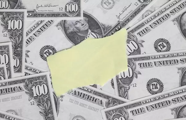 Leeres gelbes Papierstück auf Hintergrund aus Banknoten