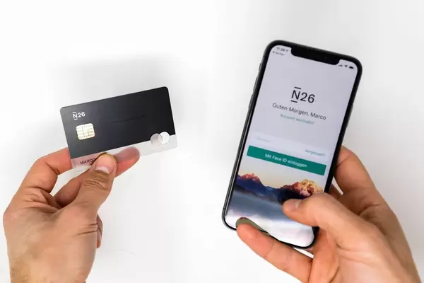 Left hand shows N26 Black bank card while right hand shows Iphone with the N26 mobile app